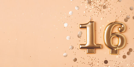 Gold candles in the form of number sixteen on peach background with confetti. 16 years celebration.の写真素材