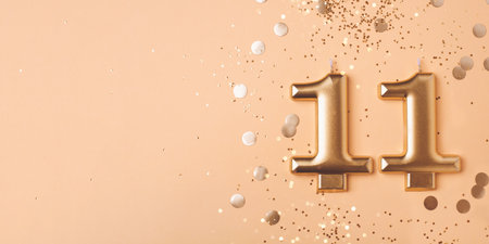 Gold candles in the form of number eleven on peach background with confetti. 11 years celebration.の写真素材