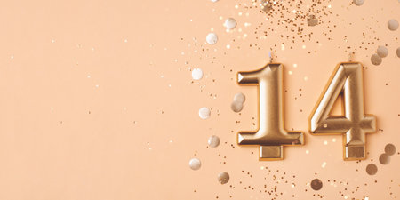 Gold candles in the form of number fourteen on peach background with confetti. 14 years celebration.の写真素材
