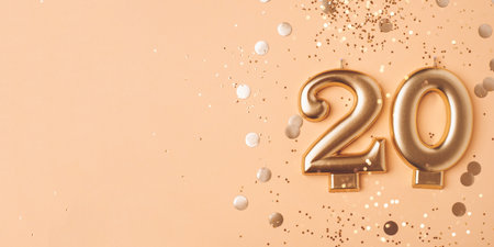 Gold candles in the form of number twenty on peach background with confetti. 20 years anniversary celebration.の写真素材