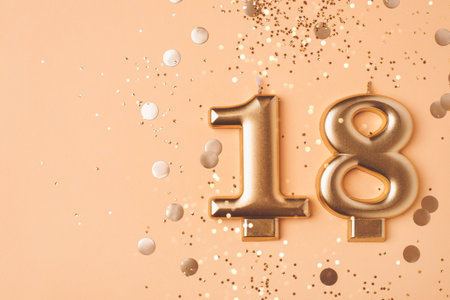Gold candles in the form of number eighteen on peach background with confetti. 18 years celebration. Greeting banner.の写真素材
