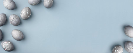 Festive Easter background. Gray-blue Easter eggs with stars on a blue table. Banner with a place for text. Top view.の写真素材