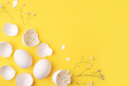 Minimalistic Easter background. White Easter eggs, shells and flowers on a bright yellow background. Card with a place for text. Top view.の写真素材