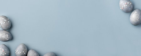 Festive Easter background. Gray-blue Easter eggs with stars on a blue table. Banner with a place for text. Top view.の写真素材