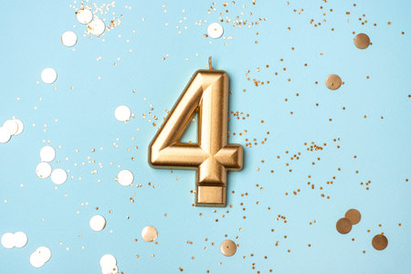 Gold candle in the form of number four on blue background with confetti.の写真素材