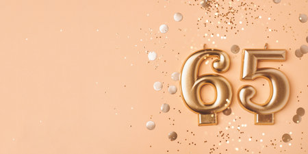 65 years celebration. Greeting banner. Gold candles in the form of number sixty five on peach background with confetti.の写真素材