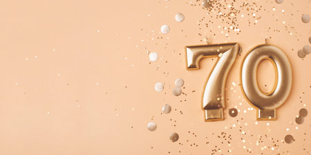 70 years celebration. Greeting banner. Gold candles in the form of number seventy on peach background with confetti.の写真素材