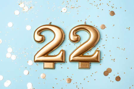 22 years celebration. Greeting banner. Gold candles in the form of number twenty two on blue background with confetti.の写真素材