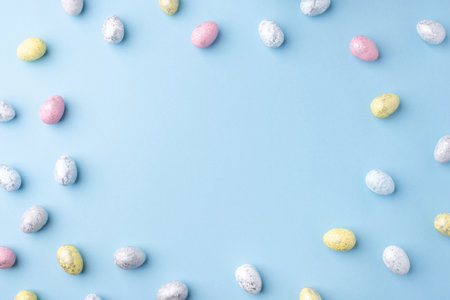 Festive Easter background. Multicoloured Easter eggs on a blue table. Card with a place for text. Top view.の写真素材