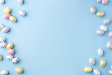 Festive Easter background. Multicoloured Easter eggs on a blue table. Card with a place for text. Top view.の写真素材