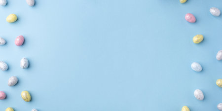 Festive Easter background. Multicoloured Easter eggs on a blue table. Banner with a place for text. Top view.の写真素材
