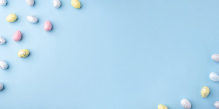 Festive Easter background. Multicoloured Easter eggs on a blue table. Banner with a place for text. Top view.の写真素材