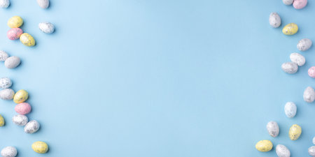 Festive Easter background. Multicolored Easter eggs on a blue table. Banner with a place for text. Top view.の写真素材