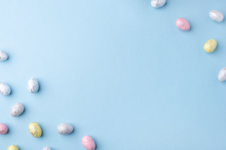 Festive Easter background. Multicolored Easter eggs on a blue table. Card with a place for text. Top view.の写真素材
