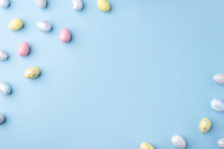 Festive Easter background. Multicolored Easter eggs on a blue table. Card with a place for text. Top view.の写真素材