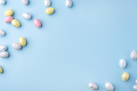 Festive Easter background. Multicolored Easter eggs on a blue table. Card with a place for text. Top view.の写真素材