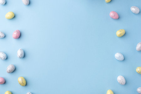 Festive Easter background. Multicolored Easter eggs on a blue table. Card with a place for text. Top view.の写真素材