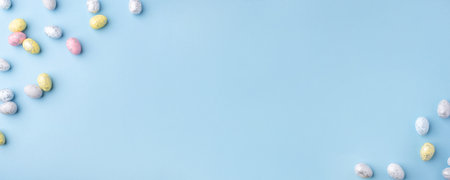 Festive Easter background. Multicolored Easter eggs on a blue table. Banner with a place for text. Top view.の写真素材