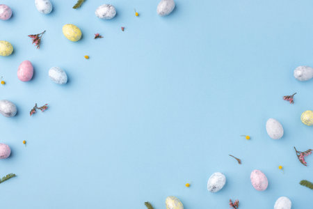 Festive Easter background. Multicolored Easter eggs on a blue table. Card with a place for text. Top view.の写真素材