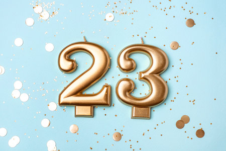 23 years celebration. Greeting banner. Gold candles in the form of number twenty three on blue background with confetti.の写真素材