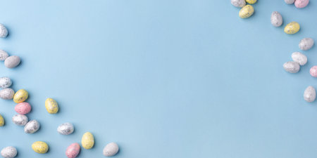 Festive Easter background. Multicolored Easter eggs on a blue table. Banner with a place for text. Top view.の写真素材