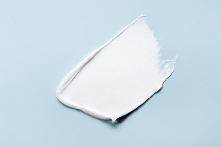White smear of cream, mask or balm on a blue background. The texture of the skin or hair care product.の写真素材