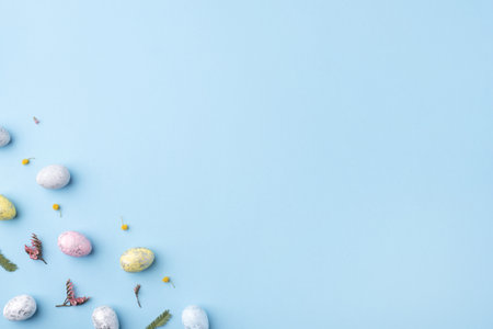 Festive Easter background. Multicolored Easter eggs and flowers on a blue table. Banner with a place for text. Top view.の写真素材