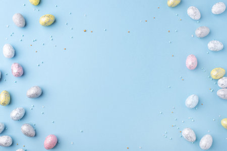 Festive Easter background. Multicolored Easter eggs on a blue table. Banner with a place for text. Top view.の写真素材