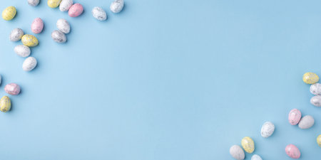 Festive Easter background. Multicolored Easter eggs on a blue table. Card with a place for text. Top view.の写真素材