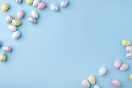 Festive Easter background. Multicolored Easter eggs on a blue table. Card with a place for text. Top view.の写真素材