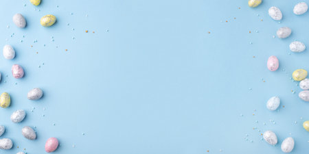 Festive Easter background. Multicolored Easter eggs on a blue table. Banner with a place for text. Top view.の写真素材