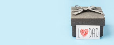 A gray gift box with a Father's Day greeting card on a blue background.の写真素材