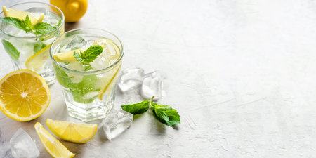 Two glasses of lemonade adorned with ice, lemon slices, and fresh mint leaves, evoking a refreshing summer vibe. Highlighting cooling drinks and seasonal enjoyment.の写真素材