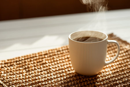 A steaming cup with a hot drink in the sunlight on the table. Morning tea or coffee.の写真素材