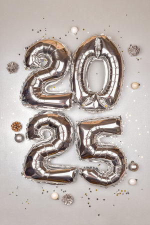 2025 Silver Balloon Numbers with Holiday Decorations. Festive New Year Celebration Theme with Metallic Ornaments and Star Confettiの写真素材