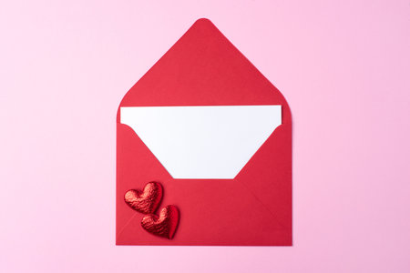 Red greeting envelope with empty white sheet on pink background