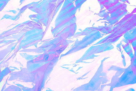 A vibrant abstract background featuring crumpled foil with a pastel gradient of pink, blue, and purple hues.の写真素材