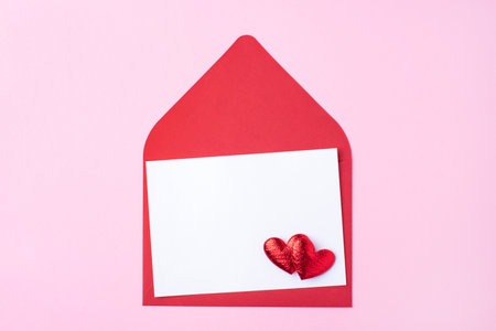 Red greeting envelope with empty white sheet on pink backgroundの写真素材
