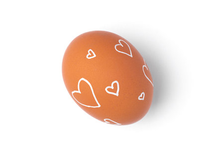 One Easter egg is a natural brown color with a minimalistic white pattern in the form of hearts isolated on a white background.の写真素材