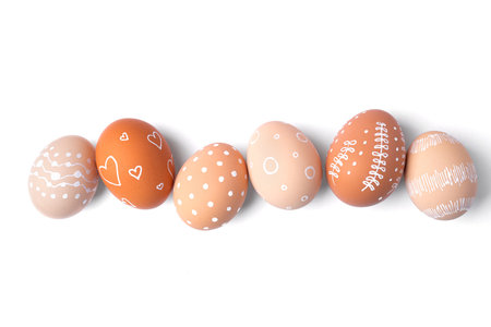Natural brown Easter eggs with white minimalist patterns (hearts, dots, and lines) isolated on a white backgroundの写真素材
