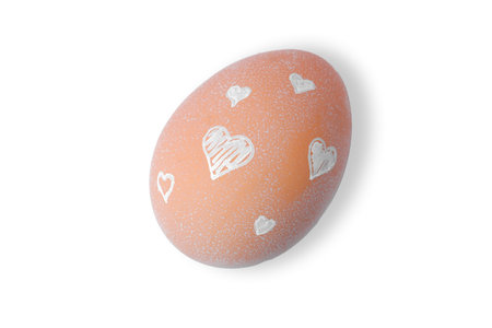 One Easter egg is a natural beige color with a minimalistic white pattern in the form of hearts isolated on a white background.の写真素材