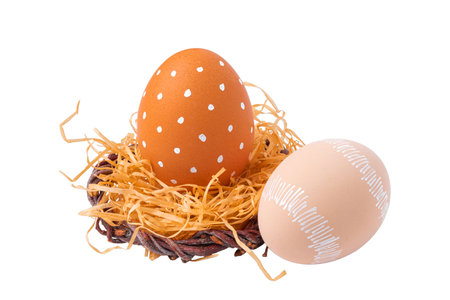 Easter eggs with a white ornament in a nest with straw isolated on a white backgroundの写真素材
