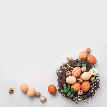 Easter nest with hand-painted eggs and quail eggs on a light background. A rustic spring composition with natural elements, fresh greenery and floral details.の写真素材