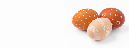 Natural brown Easter eggs with white minimalist patterns isolated on a white backgroundの写真素材