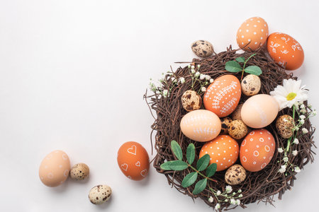 Easter nest with hand-painted eggs and quail eggs on a light background. A rustic spring composition with natural elements, fresh greenery and floral details.の写真素材