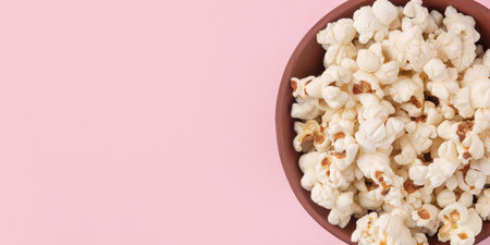 Tasty salty popcorn in a bowl on a pink backgroundの写真素材