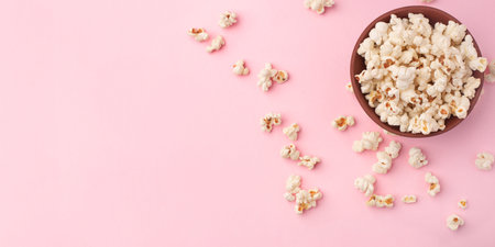 Tasty salty popcorn in a bowl on a pink backgroundの写真素材