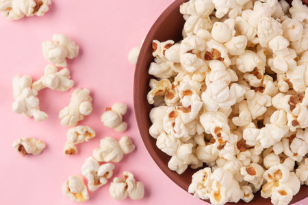 Tasty salty popcorn in a bowl on a pink backgroundの写真素材