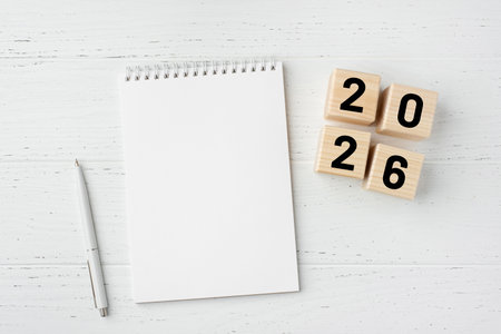 Wooden cubes with numbers for the New Year 2026 with a notebook and pen