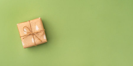A Christmas gift wrapped in eco-friendly packaging on a green backgroundの写真素材